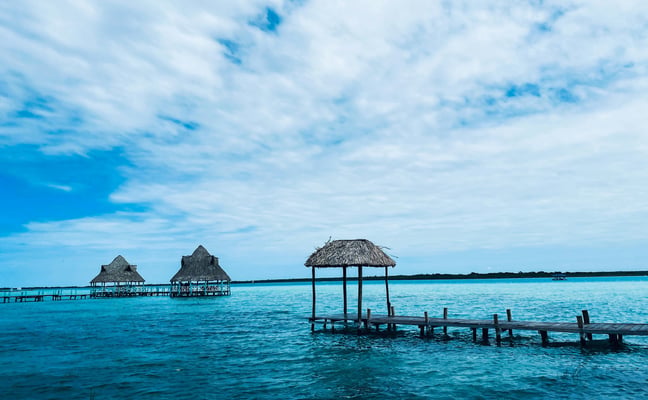 Palapa huts on wooden piers stretching into the turquoise Bacalar lagoon