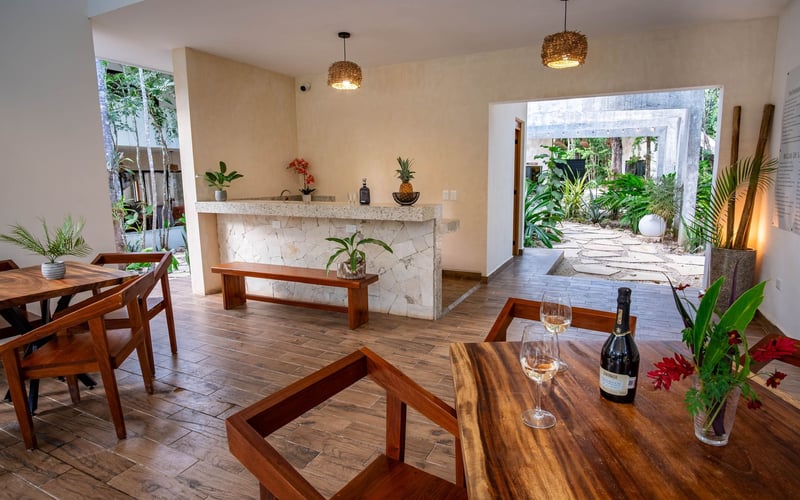 Interior dining area with bar, wooden tables and chairs, and an outdoor courtyard view.
